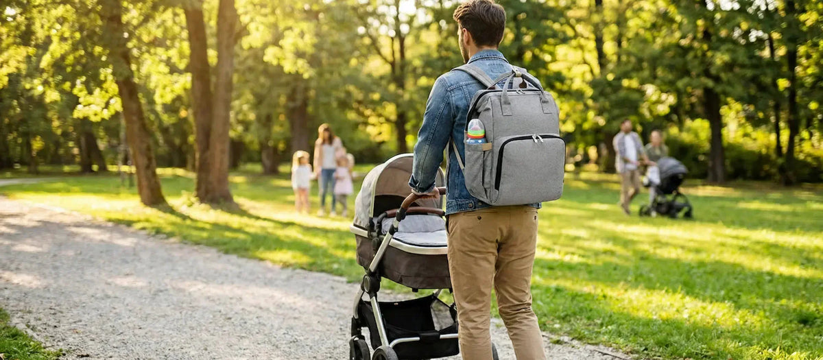 Papa portant un sac à dos à langer gris en balade avec son bébé, mains libres grâce aux bretelles réglables