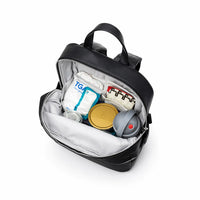Sac à dos à langer noir en cuir PU ouvert et rempli de couches, boîte de lait, biberon et accessoires, montrant les compartiments intérieurs organisés.