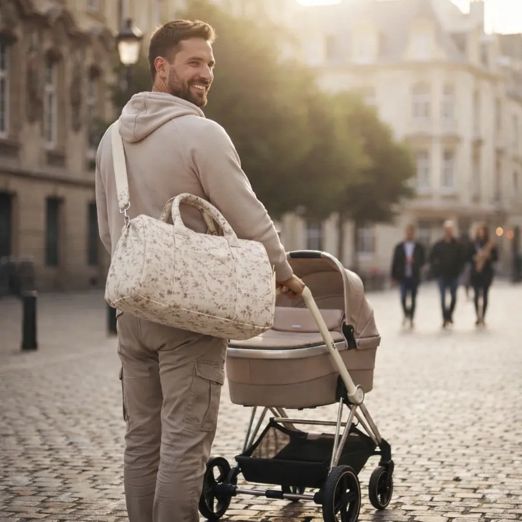 Papa poussant une poussette en centre-ville au coucher de soleil, portant un sac à langer bandoulière en gaze de coton à motif fleuri