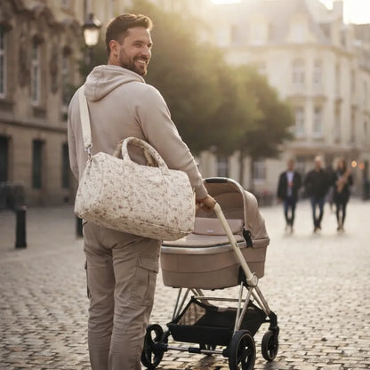 Papa poussant une poussette en centre-ville au coucher de soleil, portant un sac à langer bandoulière en gaze de coton à motif fleuri