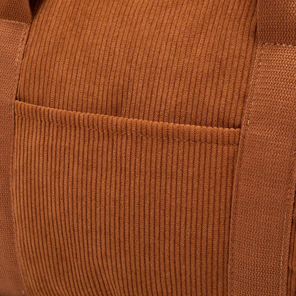 Zoom sur la poche extérieure cousue du sac à langer en velours côtelé caramel, mettant en valeur la qualité des finitions et la texture du tissu
