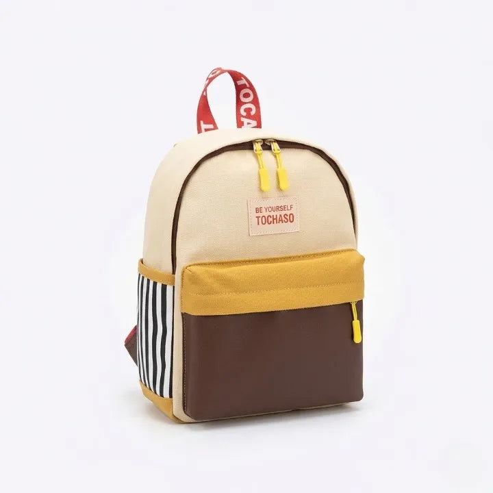 Sac à dos enfant Tochaso colorblock beige naturel, jaune et marron avec détails rayures et poignée rouge, vue de trois quarts