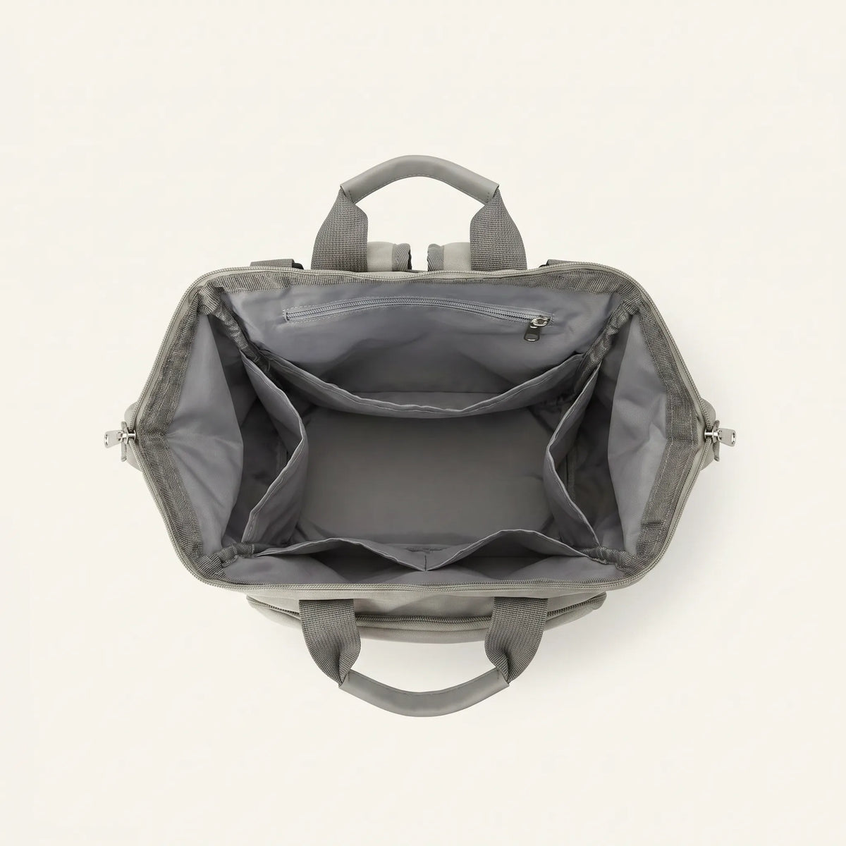 Vue de dessus du sac à dos à langer Happy Baby ouvert, compartiment principal 
vide avec doublure grise, poche zippée intérieure et structure organisée 
en 4 compartiments