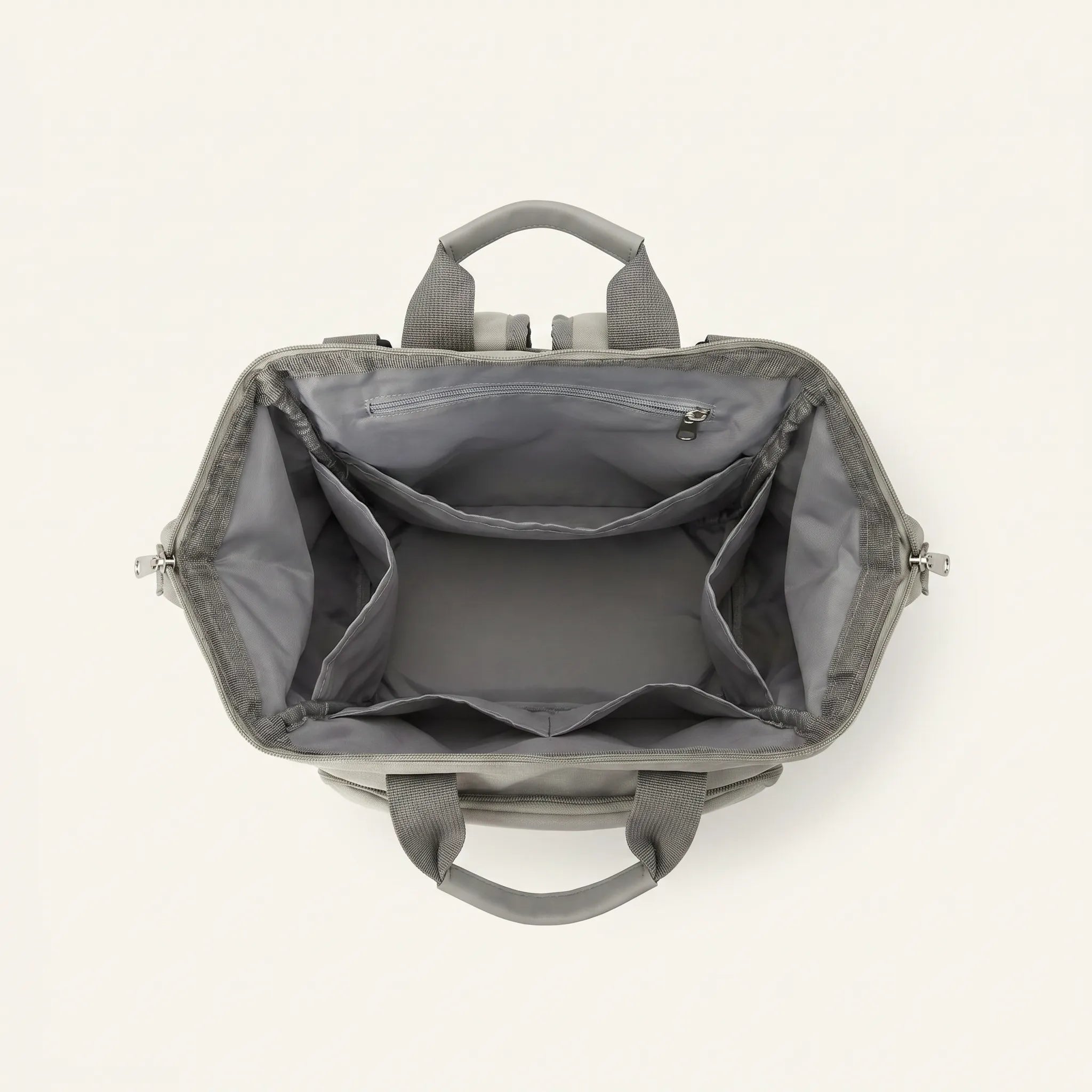 Vue de dessus du sac à dos à langer Happy Baby ouvert, compartiment principal 
vide avec doublure grise, poche zippée intérieure et structure organisée 
en 4 compartiments