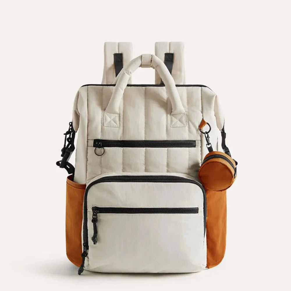 Sac à dos à langer beige et orange avec poches zippées, grandes poches latérales et petite pochette ronde amovible sur fond clair