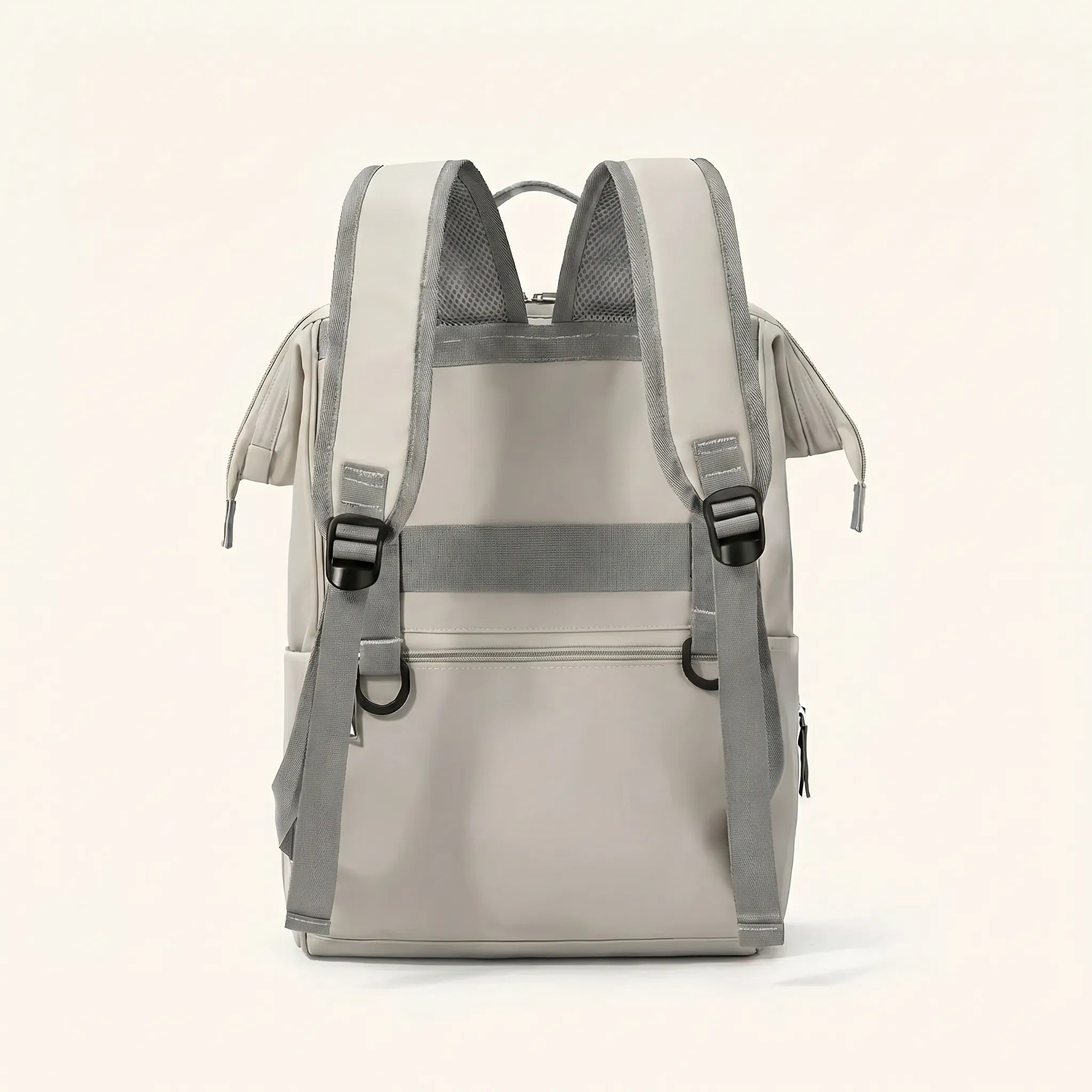 Vue de dos d'un sac à dos à langer beige crème avec bretelles ergonomiques maillées 
grises, sangle poitrine réglable et dos rembourré — design ergonomique et fonctionnel