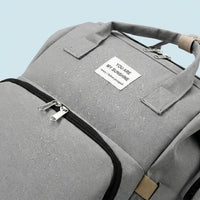 Zoom sur un sac à dos à langer gris avec gouttes d'eau sur le tissu, démontrant son imperméabilité