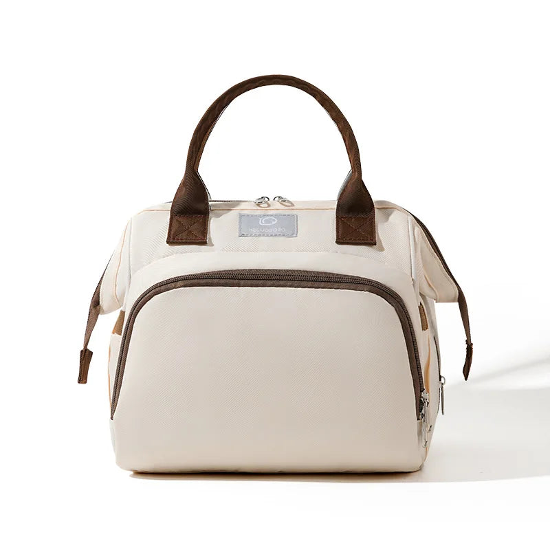 Sac à langer beige avec poignées marron et fermeture zippée, format compact pour sorties bébé, vue de face sur fond clair