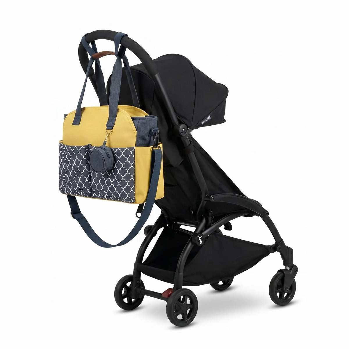Sac à langer grande capacité bleu denim moutarde et motif arabesque avec attache-tétine assorti accroché au guidon d'une poussette compacte noire de type Yoyo