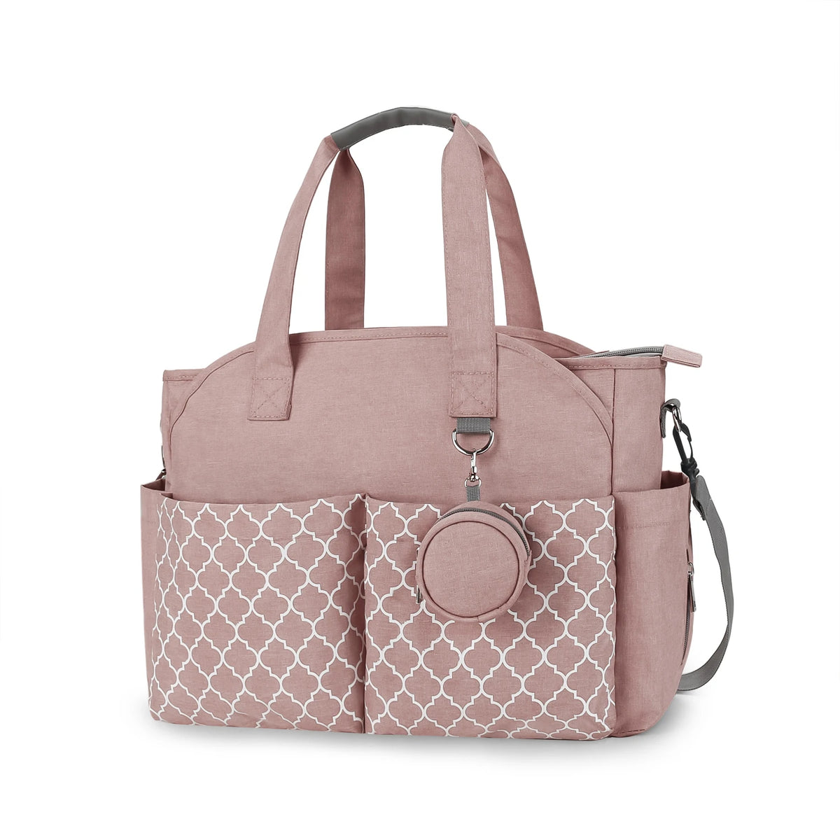 Sac à langer rose à motifs géométriques avec grandes poches avant, poignées solides et bandoulière réglable, idéal pour organiser les affaires de bébé en sortie.