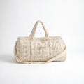 Sac maternité format polochon matelassé beige à imprimé fleuri délicat avec poignées, bandoulière ajustable et poche frontale sur fond clair