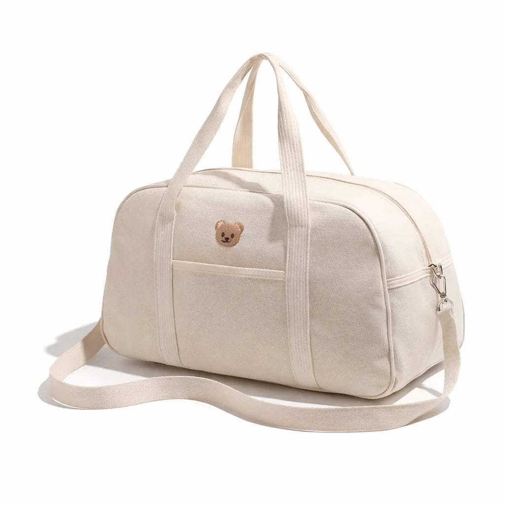 Sac week-end bébé écru en toile avec bandoulière et broderie ourson, vue de trois quarts sur fond blanc