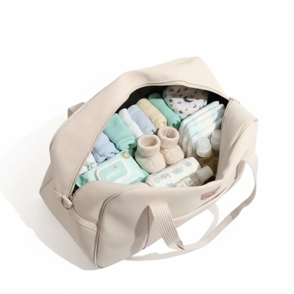 Sac week-end bébé écru ouvert montrant couches, lingettes, vêtements et produits de soin
