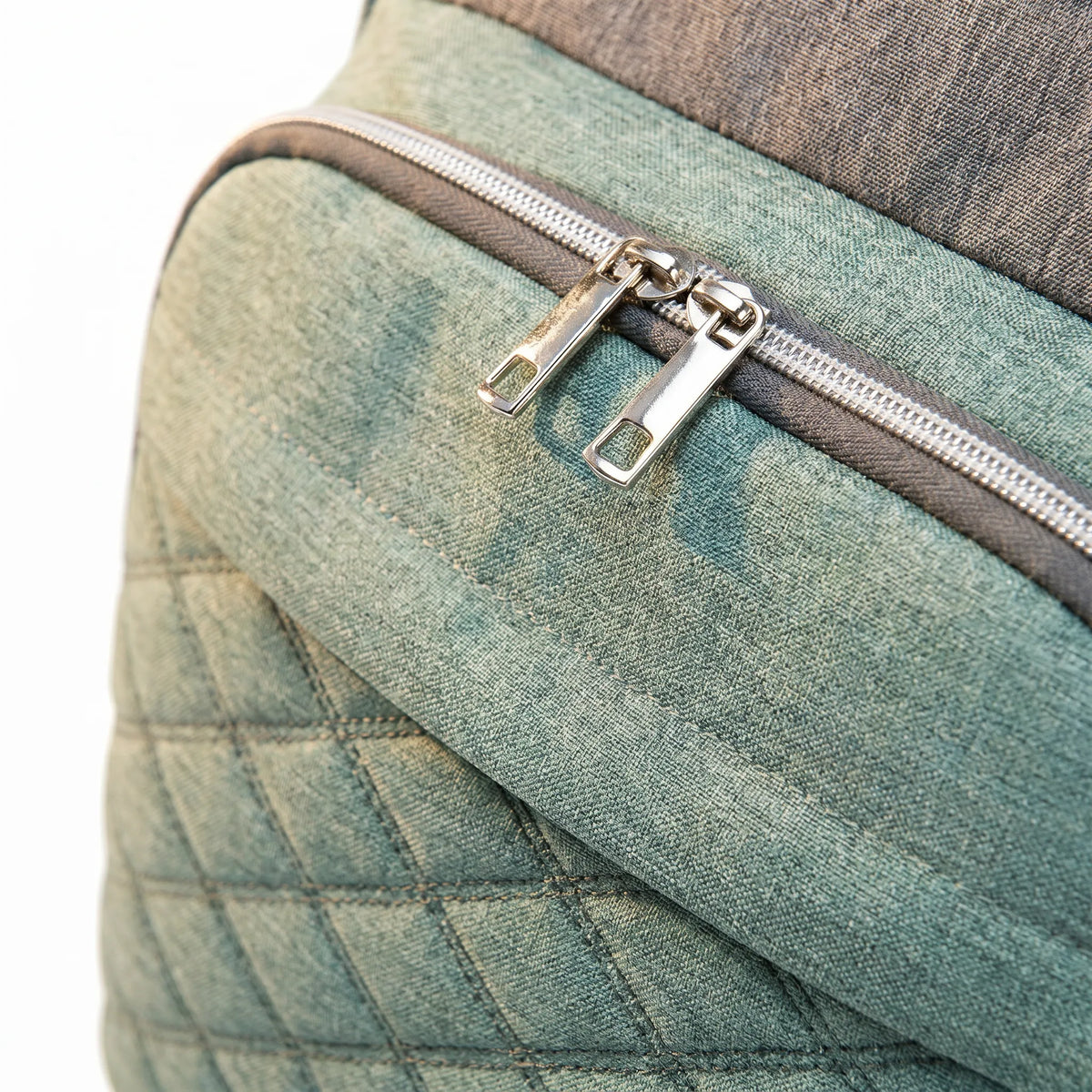 Détail macro du sac à dos à langer vert sauge montrant le motif matelassé diamant et la texture Oxford