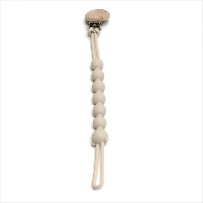 attache tétine beige sur fond blanc