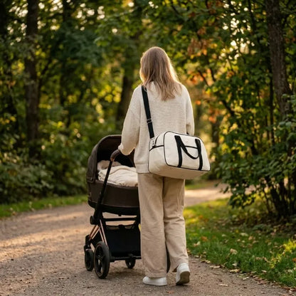 maman qui promene son bebe en poussette portant un sac à langer bandouliere via l'epaule