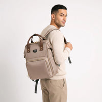 Homme portant un sac à dos à langer Sunveno beige et marron au design moderne et unisexe, idéal pour les parents actifs.