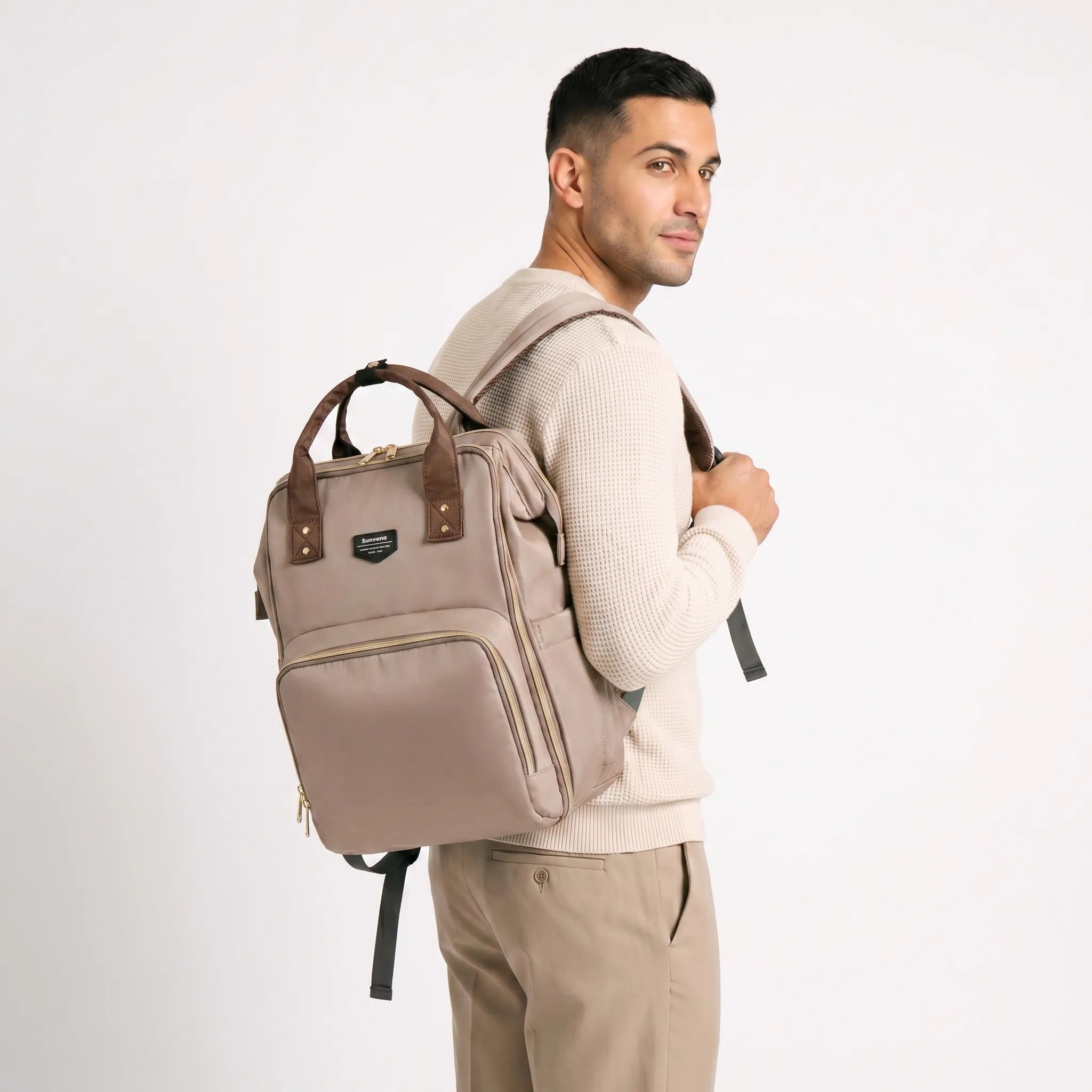 Homme portant un sac à dos à langer Sunveno beige et marron au design moderne et unisexe, idéal pour les parents actifs.