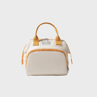 Sac à langer beige avec poignées jaunes et fermeture zippée, format compact pour sorties bébé, vue de face sur fond clair