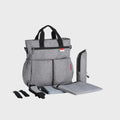sac à dos à langer gris avec tapis à langer et accessoires sur fond blanc