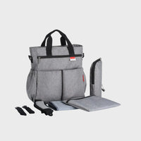 sac à dos à langer gris avec tapis à langer et accessoires sur fond blanc