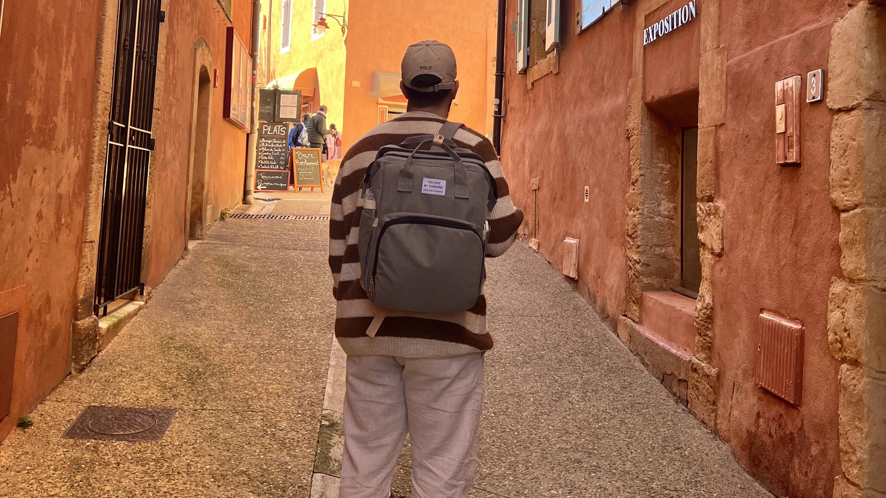 homme de dos qui porte un sac à langer à Roussillon dans le sentier des ocres